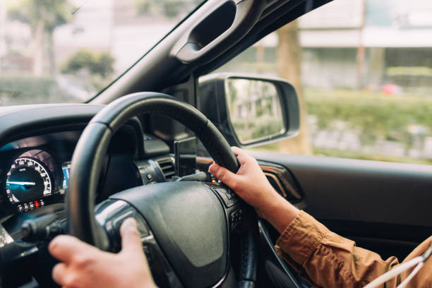 An anonymous male taxi driver waiting in his car stuck in a traffic jam holding his steering wheel.