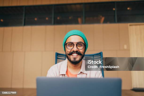 A Portrait Of A Happy Casually Dressed Man With Moustaches Looking At Camera While Sitting In His Office At Computer Stock Photo - Download Image Now