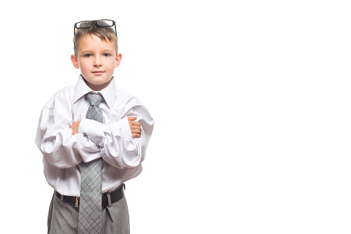 Little cute boy in a gray suit, tie and white shirt with glasses on his head is isolated on a white background. Advertising of educational courses, advanced training.