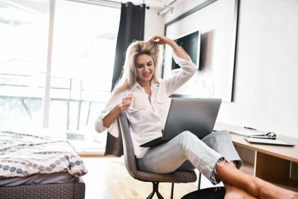 istock Blond Female Beauty Drinking Coffee While Working On Laptop At Home 1388231368
