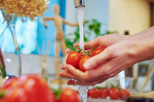 istock Woman washing tomato at kitchen sink 1388233899