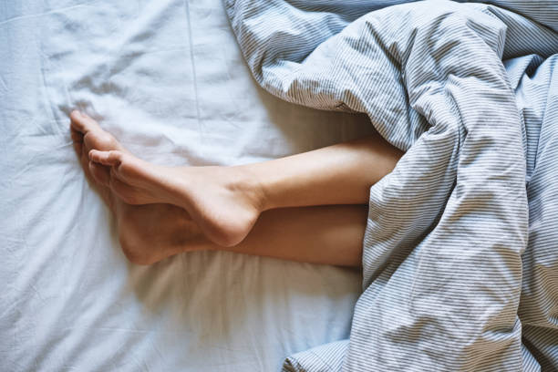 istock Female legs in the bed under blanket 1388233912
