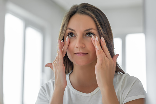 Aplicación de crema hidratante sobre la piel debajo de los ojos photo