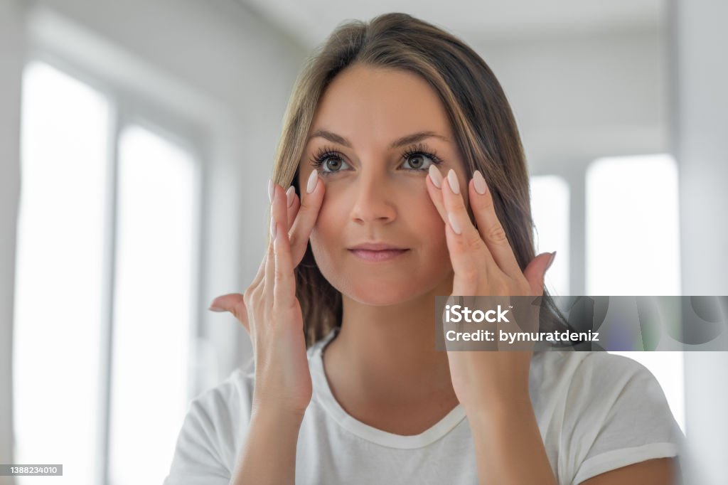 Applying moisturizing cream on under eye skin Eye Stock Photo