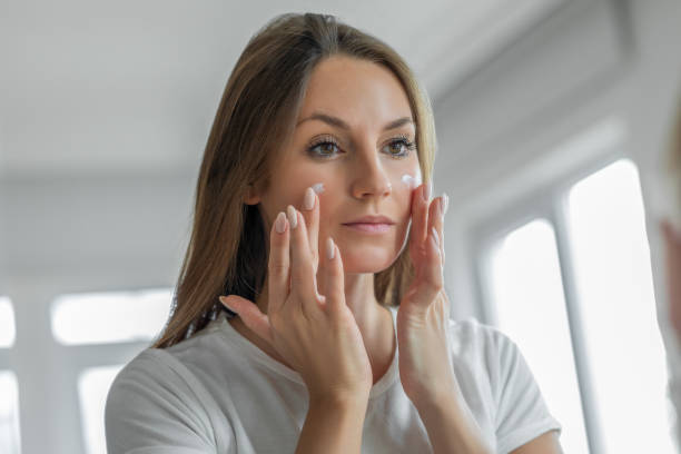 mujer aplicar crema humectante - facial cleanser fotografías e imágenes de stock