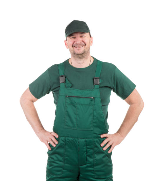 istock A worker in a green jumpsuit stands with his hands on his hips. 1388234480