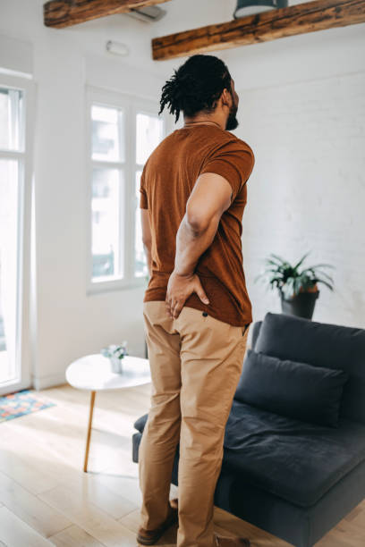 istock Man suffering from hemorrhoid in living room 1388235175