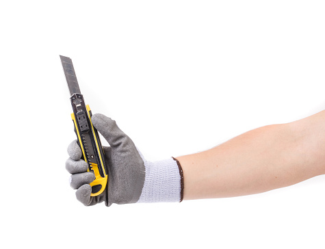 A gloved hand holds a cutter. Isolated on a white background. Close-up.