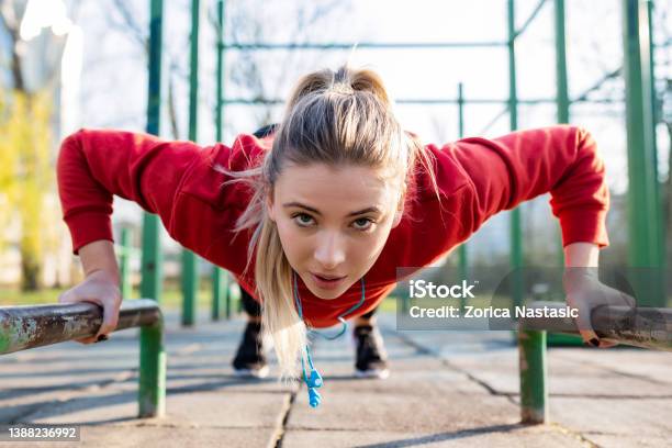 Sporty Young Woman In Sportswear Doing Bar Pushups Looking At Camera Stock Photo - Download Image Now