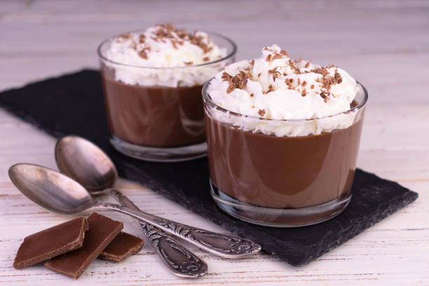 istock Chocolate pudding with whipped cream in glasses on a black slate board. 1388238292