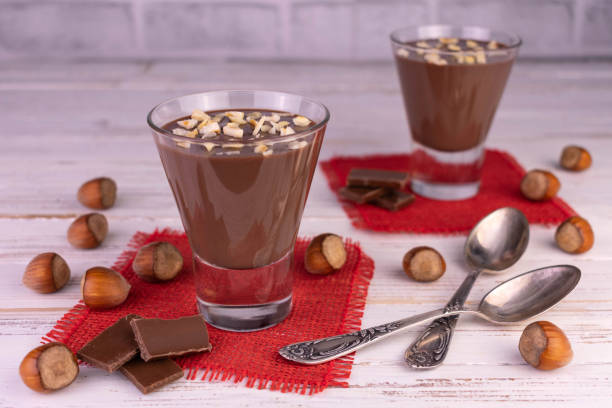 istock Chocolate mousse with hazelnuts in glasses on a white wooden background. 1388238318