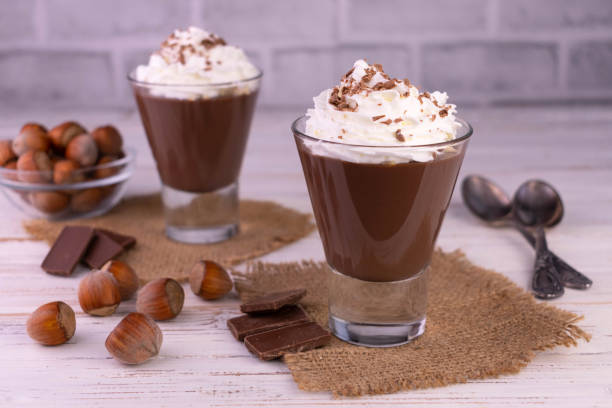 istock Chocolate mousse with hazelnuts and cream on a white wooden background. 1388238331