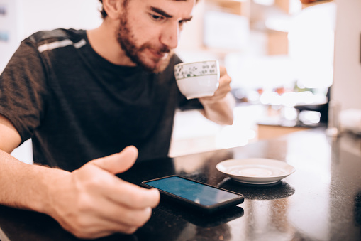 Man using phone and drinking coffee in the morning