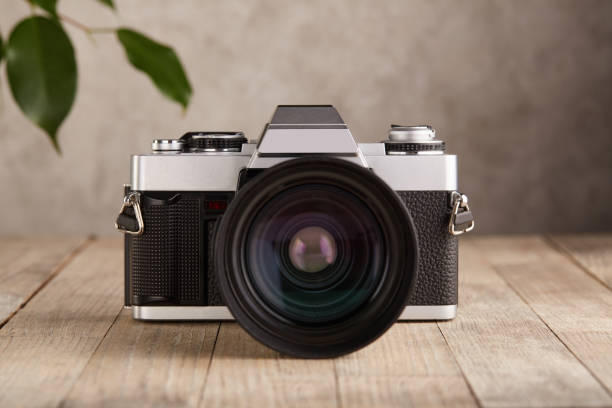 SLR Single-lens reflex professional camera on wooden table and concrete wall background SLR Single-lens reflex professional camera on wooden table and concrete wall background photographic film camera stock pictures, royalty-free photos & images