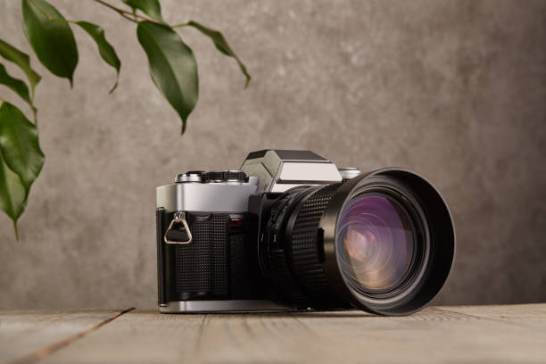 istock SLR Single-lens reflex professional camera on wooden table and concrete wall background 1388243467