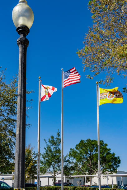 us stars & stripes, stato della florida, e osceola county, florida bandiere che sventolano in una brezza sotto un cielo blu chiaro a kissimmee, florida - us state flag national flag flag three objects foto e immagini stock