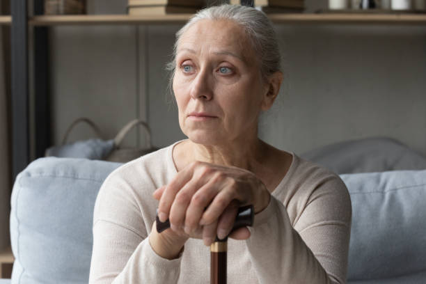 istock Depressed old woman sitting on couch, leaning on cane 1388244186