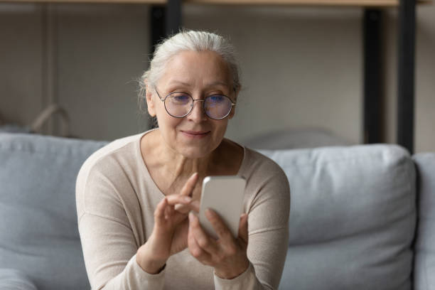 istock Happy senior woman in glasses reading text message 1388244191