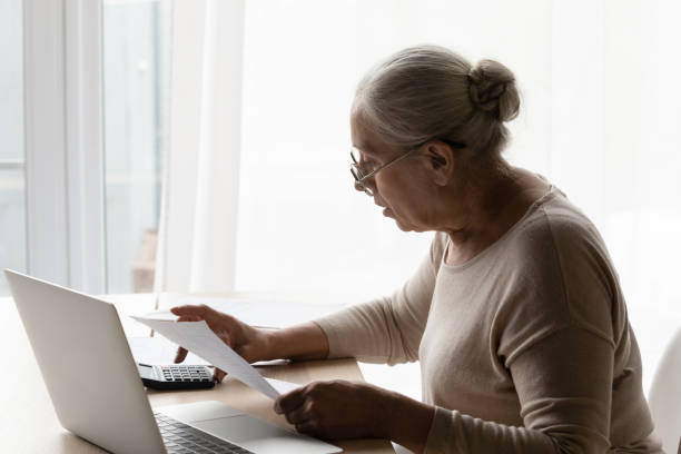 istock Senior 70s landlady, tenant lady using calculator, online banking app 1388244220