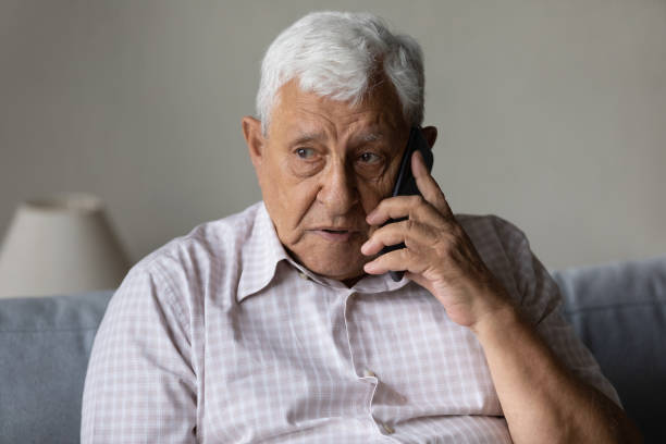 istock Serious concerned old grandpa talking on mobile phone 1388244255