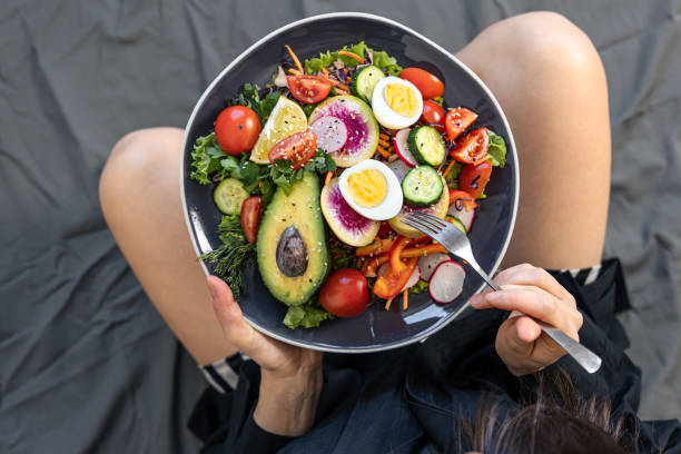 istock Appetizing salad with fresh vegetables and eggs in a plate in female hands. 1388246648