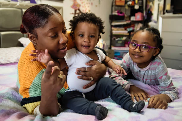 istock Mother cuddling small children on a bed at home. 1388247461