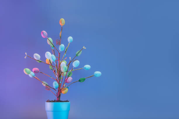 decoración del árbol de pascua en maceta azul con huevos de colores en colores neón azul. color púrpura y azul fondo festivo minimalista. semana santa moderna y moderna. enfoque selectivo. espacio de copia - easter ornament fotografías e imágenes de stock