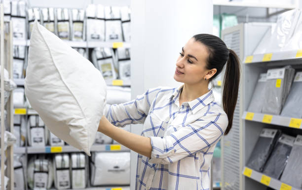 a young woman chooses a pillow in a home improvement store. - bedding merchandise market textile imagens e fotografias de stock