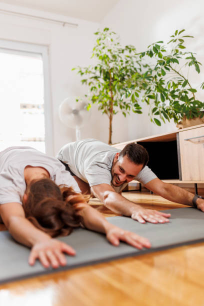 pareja haciendo yoga en casa - stretching boyfriend indoors lifestyles fotografías e imágenes de stock