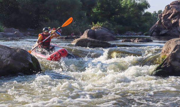 un homme ramant des sacs gonflables sur les eaux vives de la rivière de montagne. concept: sports nautiques extrêmes d’été, repos actif, rafting extrême. - rafting on a mountain river photos et images de collection