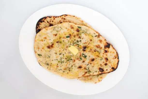 Photo of Indian Tandoori Naan Bread Also Called Amritsari Tanduri Nan Kulcha Bread Cooked In Hot Oven Tandoor Is Popular Flatbread Enjoyed In North And South India. Isolated On White Background With Copy Space