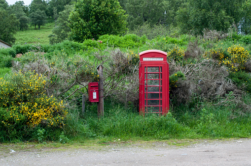 A red typical English telephone box stands in the middle of the wasteland in Scotland.