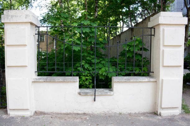 istock Black wrought iron fence between stone pillars 1388251700