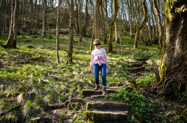 kobieta z avietnamese idzie stromą zalesioną ścieżką w cressbrook dale w peak district nation al park, derbyshire, wielka brytania - steep road footpath moving down zdjęcia i obrazy z banku zdjęć