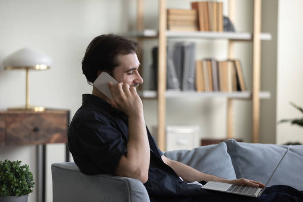 istock Happy positive young entrepreneur man resting on sofa, using gadgets 1388253772