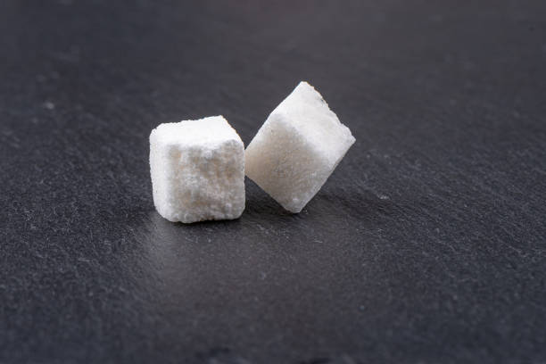istock Cubes of white beet sugar refined on a stone background. 1388254080