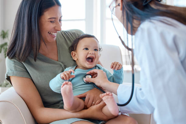 foto de un bebé sentado en el regazo de su madre mientras es examinado por un médico - niño fotografías e imágenes de stock