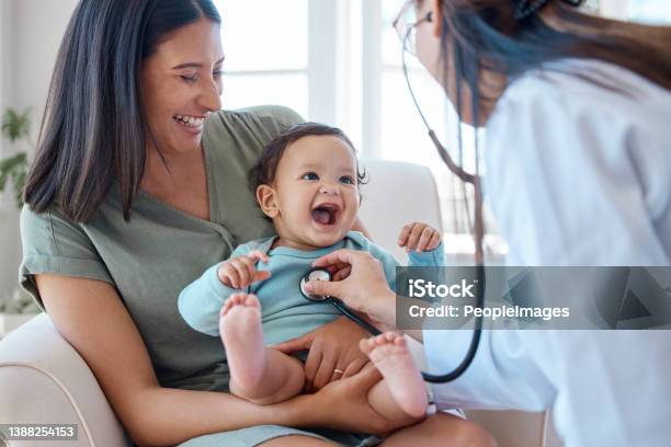 Shot Of A Baby Sitting On Her Mothers Lap While Being Examined By A Doctor Stock Photo - Download Image Now