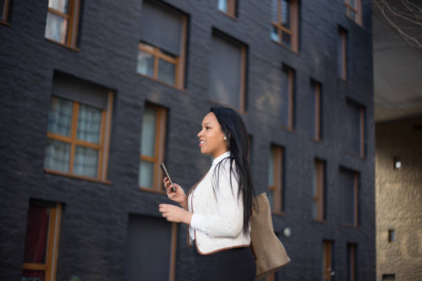 istock Young businesswoman using phone outdoors at the modern office district 1388254247