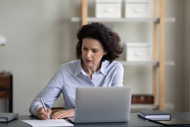 istock Focused mature business leader woman working with documents at workplace 1388254318