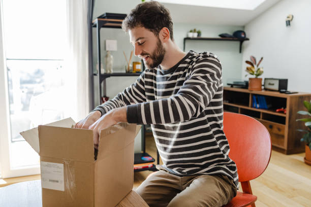 istock Young man unpacks the box with online ordered items 1388254489
