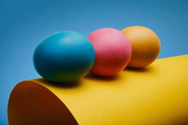 istock Colorful three Easter eggs on a rolled sheet of paper against a blue background 1388254492
