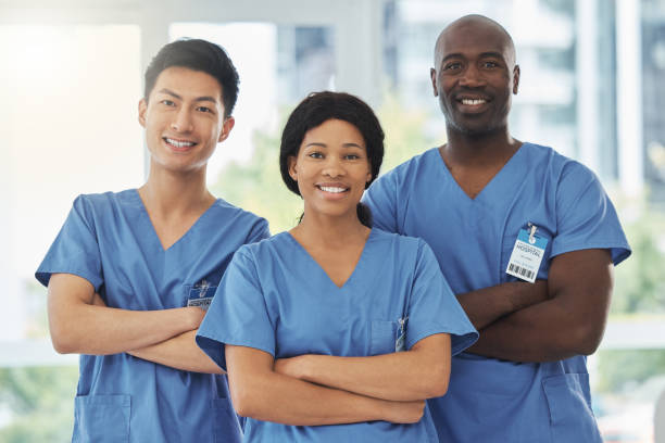 portrait d’un groupe de médecins debout ensemble, les bras croisés dans un hôpital - vêtements professionnels hospitaliers photos et images de collection