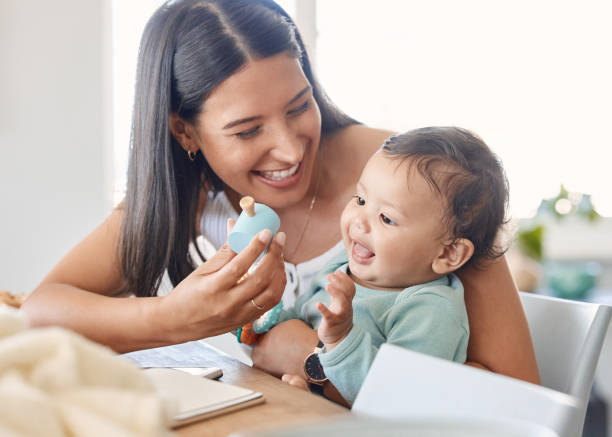 foto de una joven madre que se une a su bebé en casa - playing playful baby contemporary fotografías e imágenes de stock