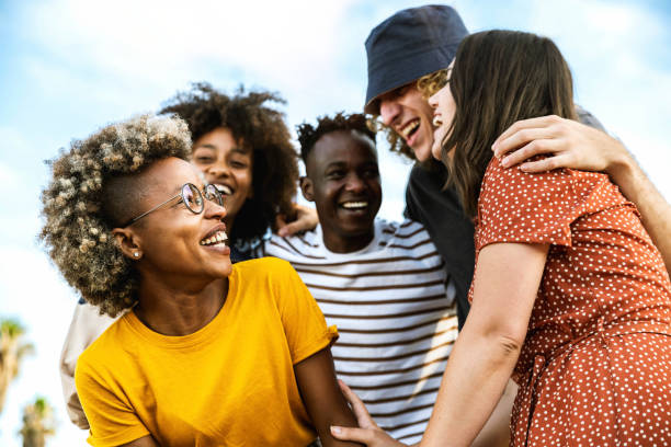 happy multiracial friends laughing out loud together - different young people having fun walking outdoors - friendship concept with guys and girls socializing and joking outside - group of people women beach community imagens e fotografias de stock