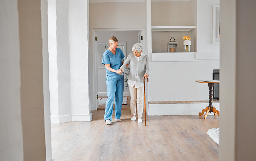 Foto de una enfermera ayudando a una mujer mayor con un bastón en una casa de retiro photo