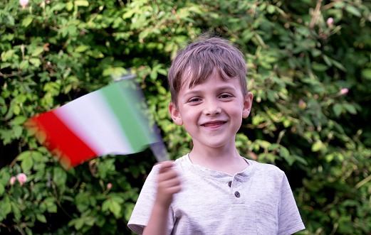 Smiling caucasian boy waving an italian flag looking at the camera