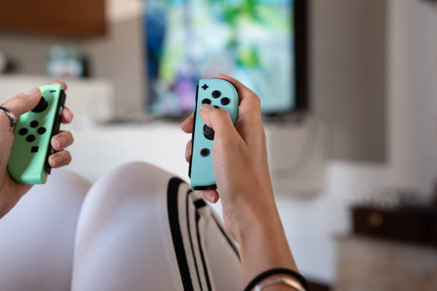 young girl playing at home with Nintendo Switch special edition - selective focus young girl playing at home with Nintendo Switch special edition - selective focus brand name games console stock pictures, royalty-free photos & images