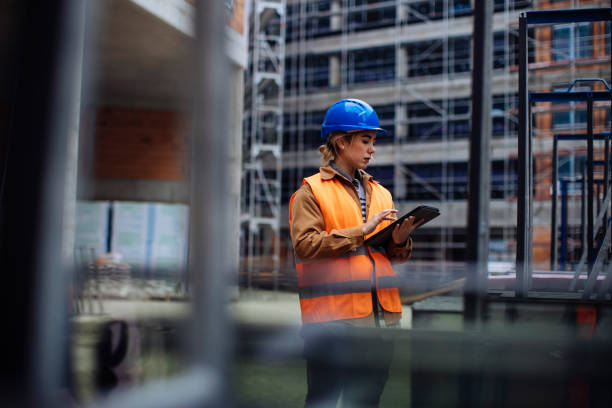 Leading by example Young female worker using her digital tablet at a construction site occupational safety and health stock pictures, royalty-free photos & images