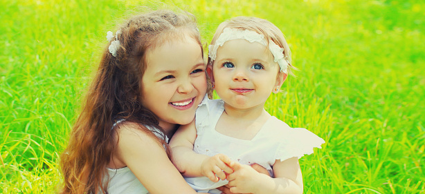 Portrait of happy smiling two little sister girls children together in summer park